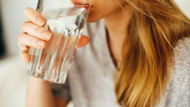 A woman drinking a glass of water to stay hydrated and healthy